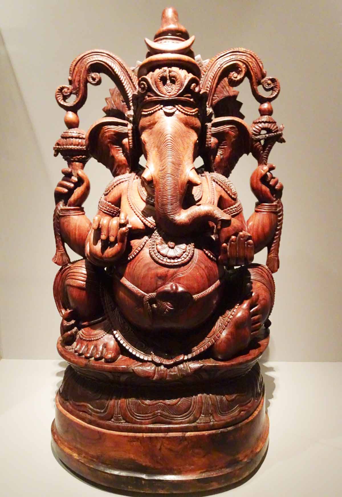 Ganescha geschnitzt, die Gottheit wird als Helefant mit dickem Bauch, Gürtel, aufwändigem Kopfschmuck, 4 Armen und 2 Beinen dargestellt